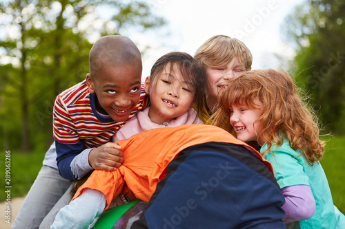 Group of kids is grabbing a ball in the park © Robert Kneschke