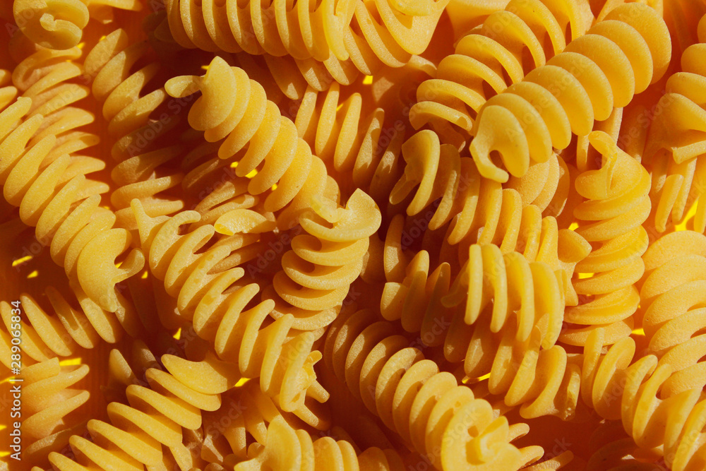 Food background. Pasta fusilli on yellow background. Colorful background. Food and diet concept. Food background. Pasta fusilli on yellow background. Colorful background. Food and diet concept.