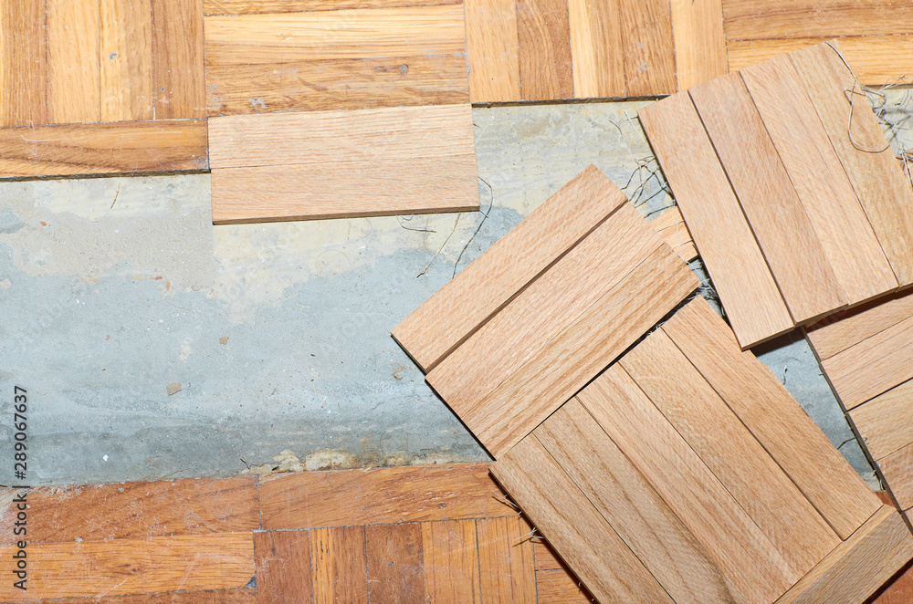 Renovation of a damaged parquet while fixing new wooden tiles instead of old - obrazy, fototapety, plakaty 