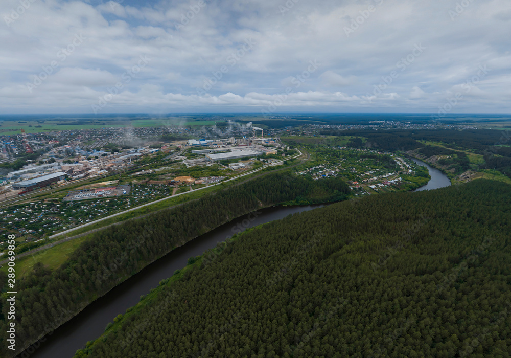 Fototapeta premium Sukhoy Log city, Pyshma river, dark forest and cement factory. Russia, Aerial, cloudu day