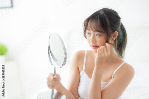 Beautiful face young asian woman with happy smiling and looking mirror, makeup of beauty facial girl with skincare and cosmetic treatment, refresh of female and clean for charming, healthy concept.