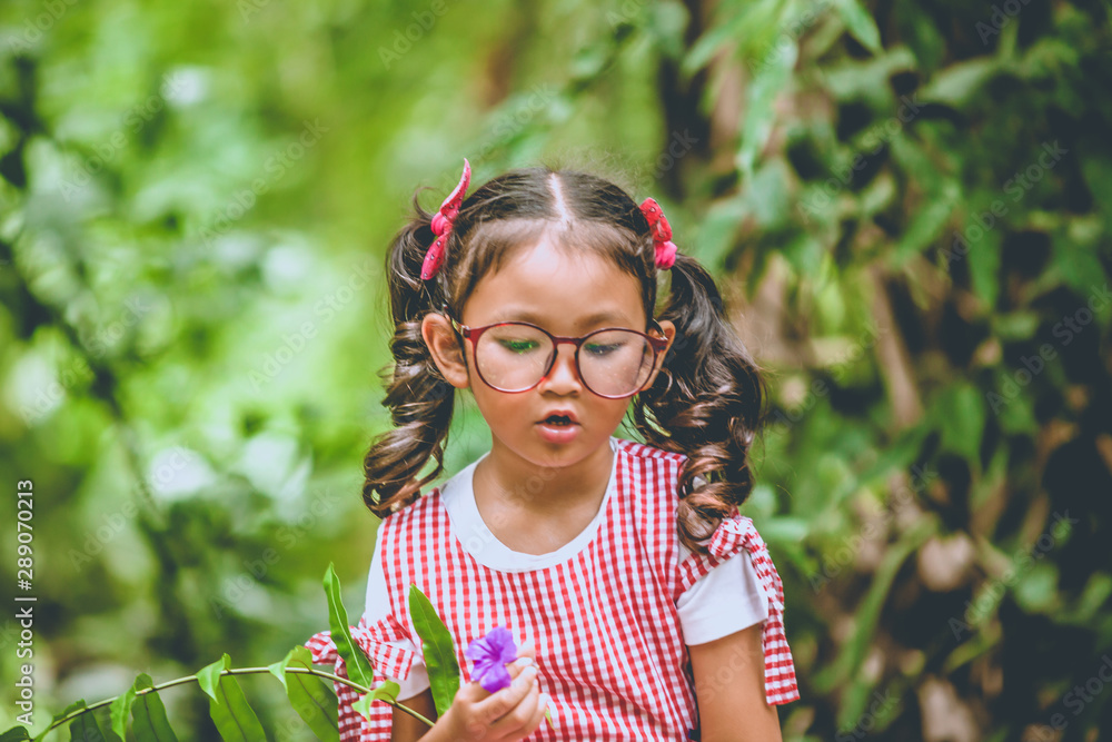 An Asian girl in pink dress wearing bright glasses sitting in the garden. An Asian girl in pink dress wearing bright glasses sitting in the garden.