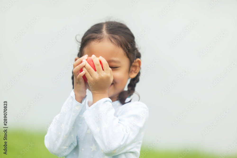 people, children, healthy eating and food concept- happy girl holding red apple over summer people, children, healthy eating and food concept- happy girl holding red apple over summer
