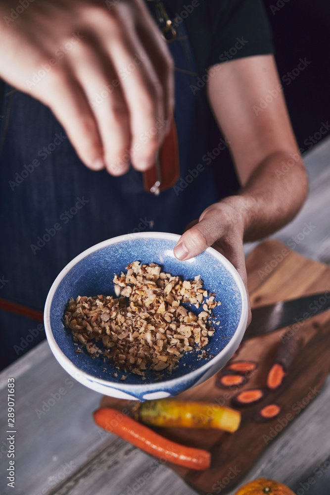 Young chef in kitchen holding bowl with walnut and preparing dinner. Food concept. Young chef in kitchen holding bowl with walnut and preparing dinner. Food concept.