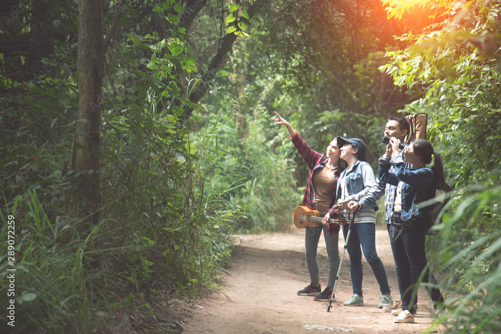 Obraz premium Friends or tourists with colorful backpacks in forest. Summer vacation. Travelling, hiking