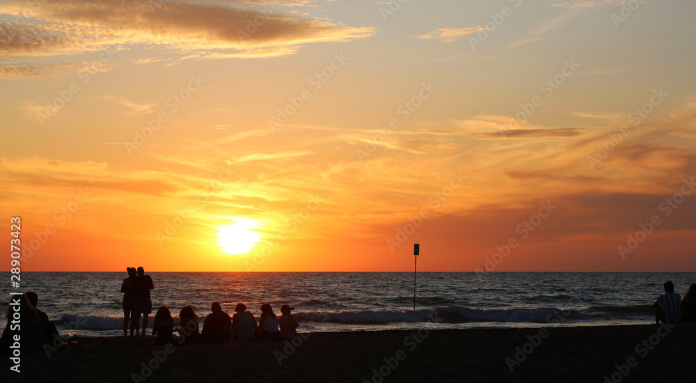 Italia, regione Toscana. Persone sulla spiaggia al tramonto