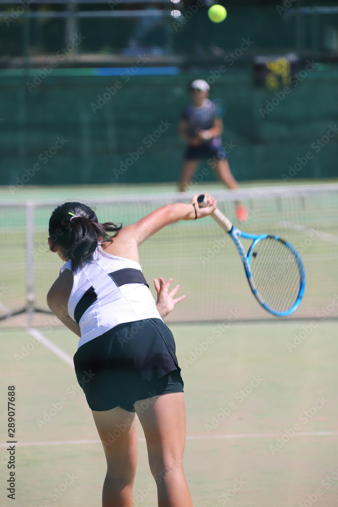 サーブを打つ女子テニスプレイヤー