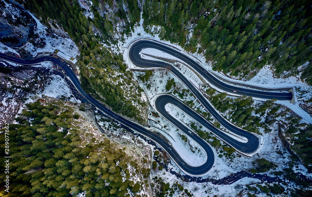 Aerial drone view of a serpentine in rocky mountain forest, Bicaz gorge with winding road in winter season,Cheile Bicazului, Romania