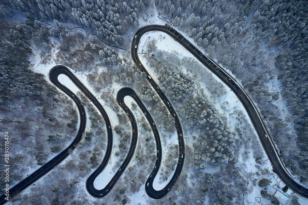Aerial drone view of a serpentine in Predeal mountain road whit forest covered in snow on winter season, Predeal, Romania