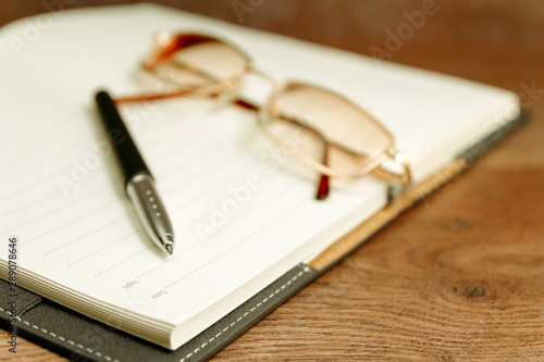 Notebook of writer and pen placed on table with vintage eyeglasses
