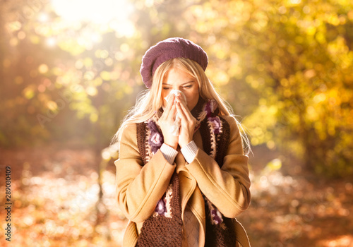 Woman coughing and blowing her nose in autumn