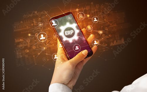Female hand holding smartphone with ERP abbreviation, modern technology concept