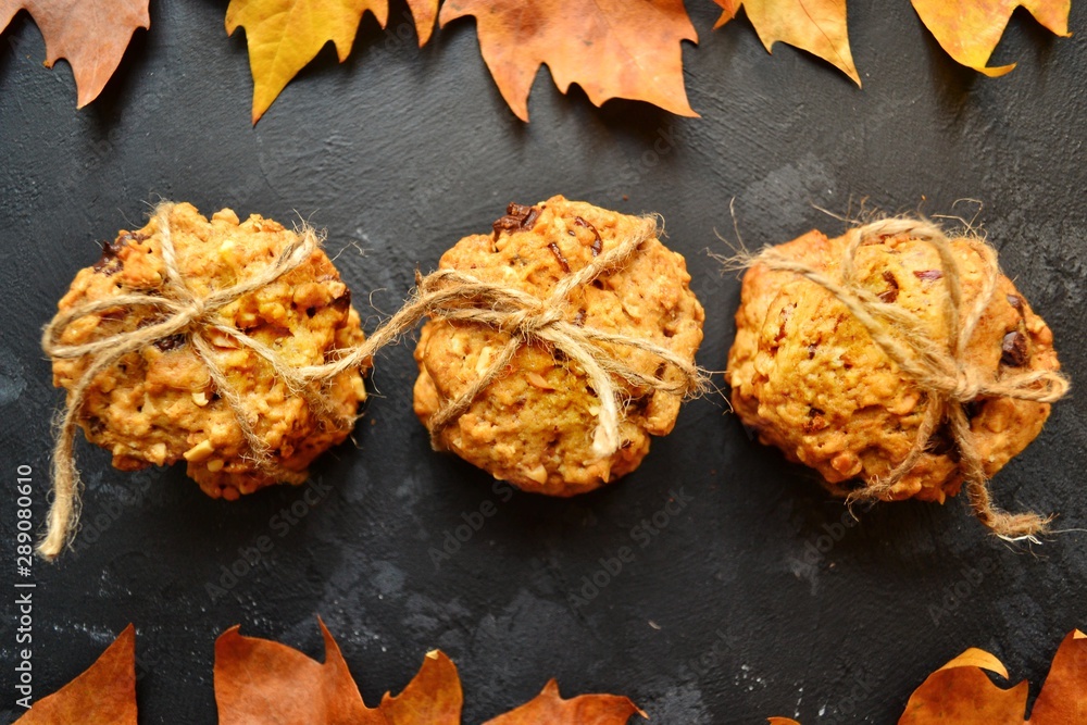 Oat cookies. Cookies on a black background with parchment. Sweet pastries with an autumn theme and autumn yellow leaves. Autumn appetizing background.