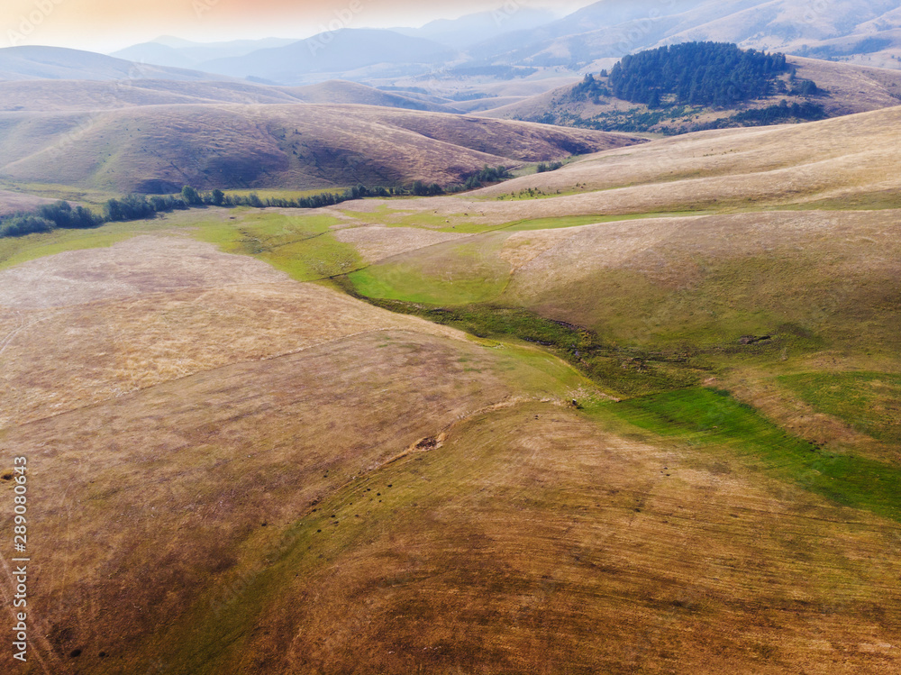 Aerial view of rural fields hills in late summer. Nature outdoors travel destination Zlatibor mountain, Serbia. Sunset sunny summer or autumn