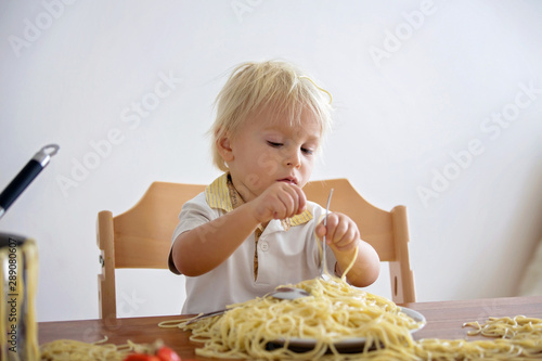 Little baby boy, toddler child, eating spaghetti for lunch and making a mess at home