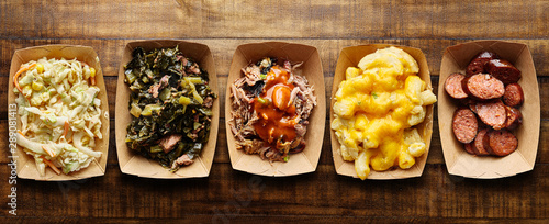assorted trays of texas bbq with collard greens, hotlinks, pulled pork, mac and cheese, coleslaw