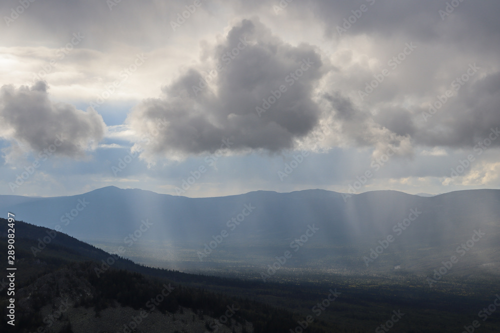 Rain, sun rays and clouds in the Ural mountains
