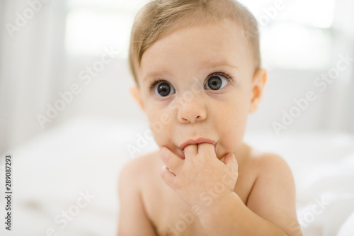 small baby boy sucking his finger on the white bedroom