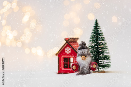 Christmas background with fir tree  house and toy man against defocused lights. Christmas or New Year celebration concept. Copy space