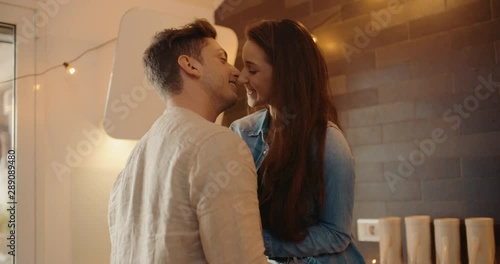 Young adult couple kissing together in the kitchen. Shot in slow motion	 photo