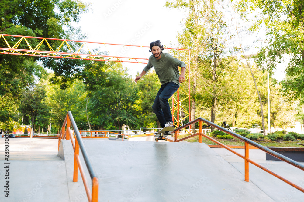 Fototapeta premium Handsome young hipster man skating on a skate ramp