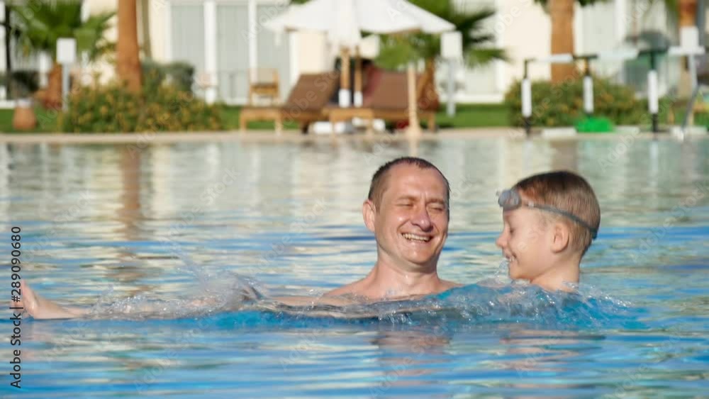 Father and son playing in pool at summer vacation. Happy family concept Father and son playing in pool at summer vacation. Happy family concept