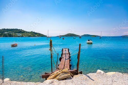 Fototapeta Naklejka Na Ścianę i Meble -  Old wooden dock reaching out in the blue waters of Skiathos