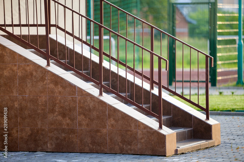 Concrete stairs covered with ceramic tiles with metal railings outdoors.