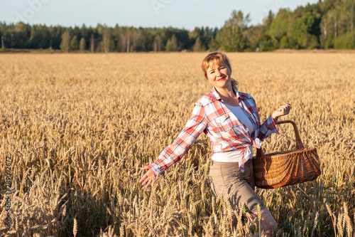 Wallpaper Mural A girl with red hair and a wicker basket in her hands is standing on a field with ripe ears of corn. Countryside and sunset. Torontodigital.ca