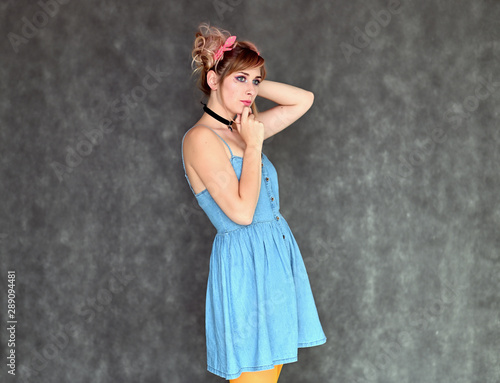 Portrait of a cute happy funny blonde girl with colored hair in a funny dress on a gray background. Smiling in various poses, beauty, holiday.