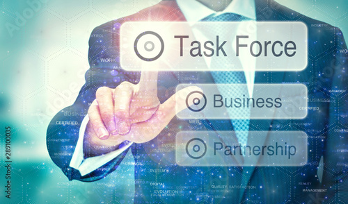 A businessman selecting a Task Force button on a futuristic display with a concept written on it.