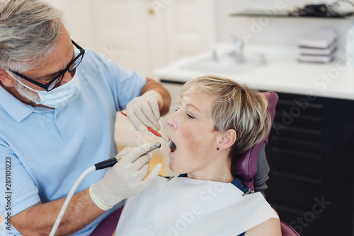 Dentist drilling the teeth of a blond woman