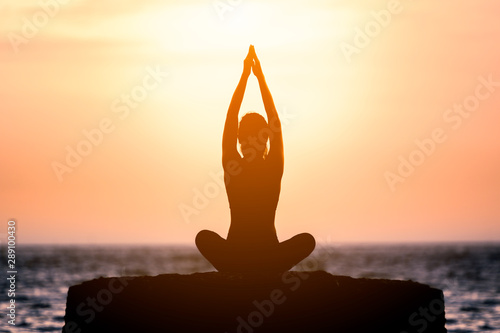 Yoga silhouette young woman on the beach at sunset.