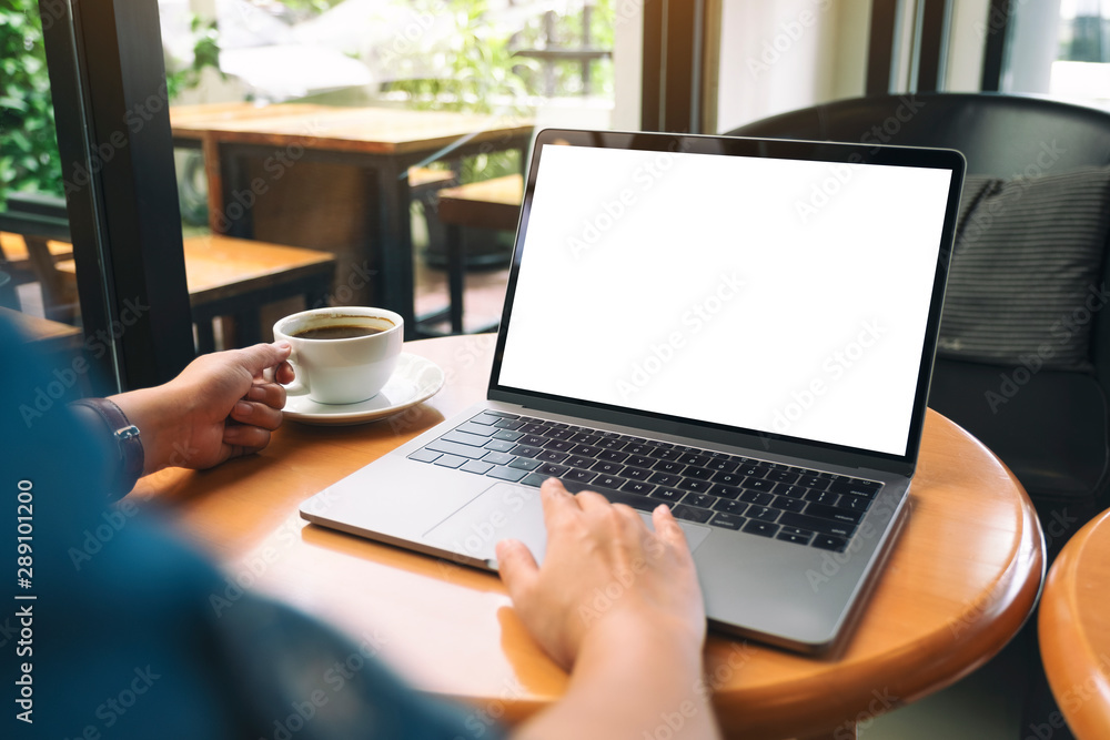 Mockup image of a woman using and touching on laptop touchpad with blank white desktop screen while drinking coffee Mockup image of a woman using and touching on laptop touchpad with blank white desktop screen while drinking coffee