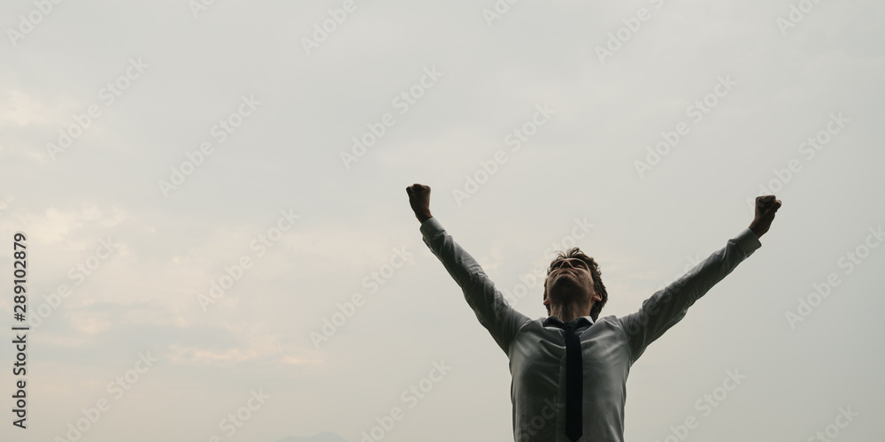 Businessman standing under sky with his arms raised Businessman standing under sky with his arms raised