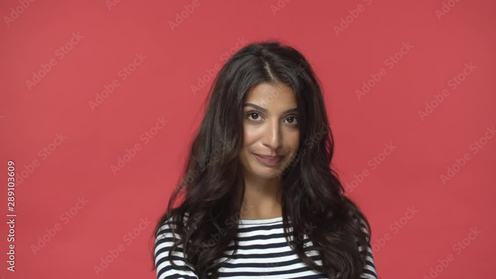 Silly feminine and sensual indian woman with dark long hairstyle, shifting eyes sideways and down, smiling acting arrogant and snobbish, knowing own worth, flirting, standing red background Silly feminine and sensual indian woman with dark long hairstyle, shifting eyes sideways and down, smiling acting arrogant and snobbish, knowing own worth, flirting, standing red background
