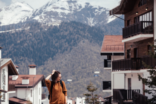 Fashionable young positive independent woman posing against a background of ski resort slopes. Concept of recreation and healthy lifestyle and the rejection of plastic