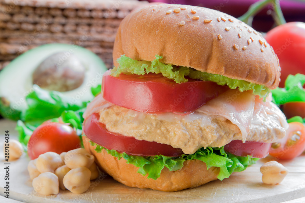 Burger with salmon and hummus on vegetable background Burger with salmon and hummus on vegetable background