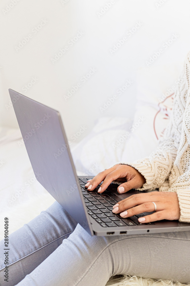 Fototapeta premium Portrait of a beautiful woman working at home in a laptop with winter outfit