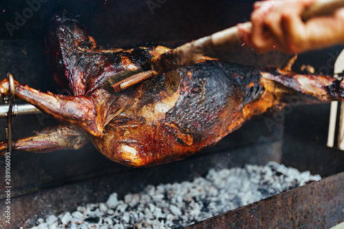 Spit roasted meat whole lamb baked on a spit direct on fire outdoor