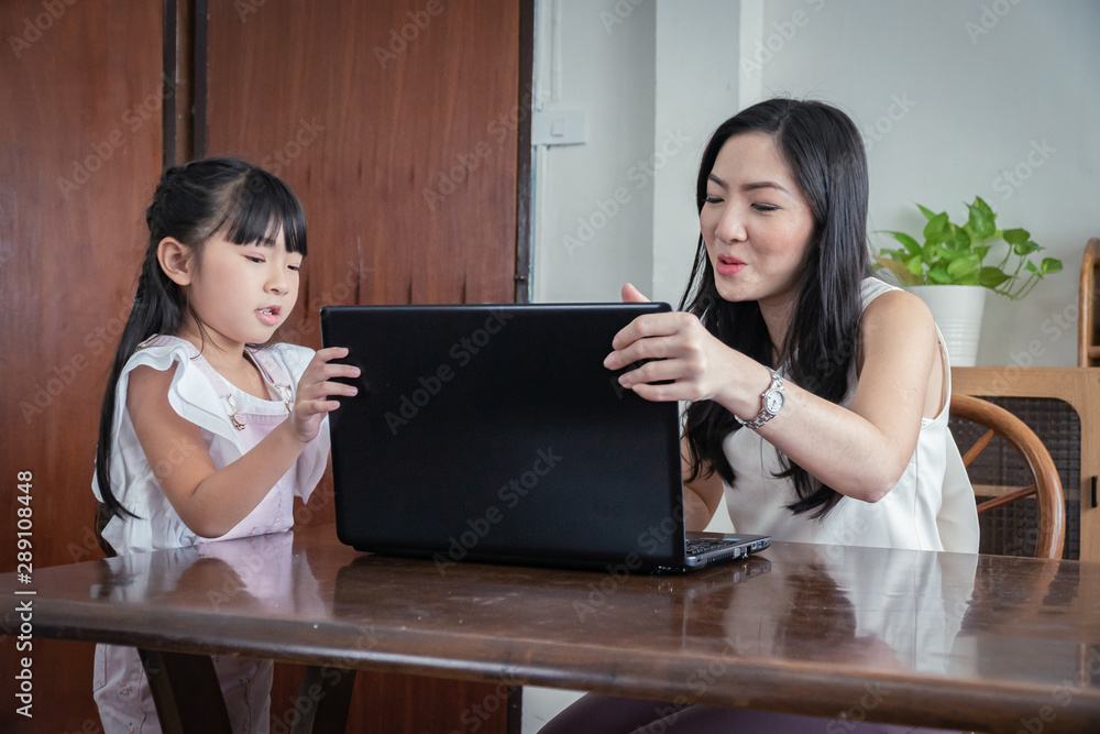 Beautiful asian mother and daughter working together at home office by the window. in concept of single mom or single parent. Beautiful asian mother and daughter working together at home office by the window. in concept of single mom or single parent.