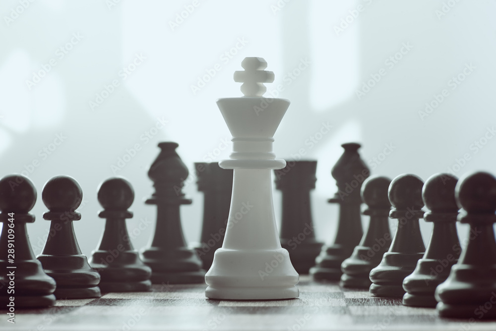 Single white king against many enemies as a symbol of difficult unequal fight or struggle of minorities. Single white king against many enemies as a symbol of difficult unequal fight or struggle of minorities.