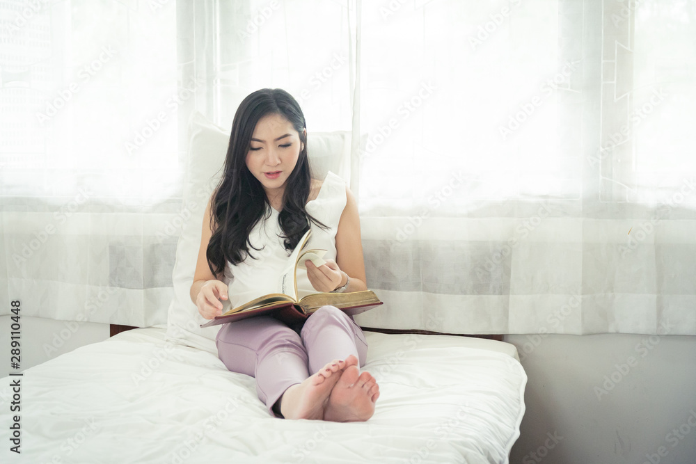 Beautiful asian girl reading book in the morning on her bed. Beautiful asian girl reading book in the morning on her bed.