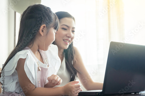 Beautiful asian mother and daughter working together at home office by the window. in concept of single mom or single parent.