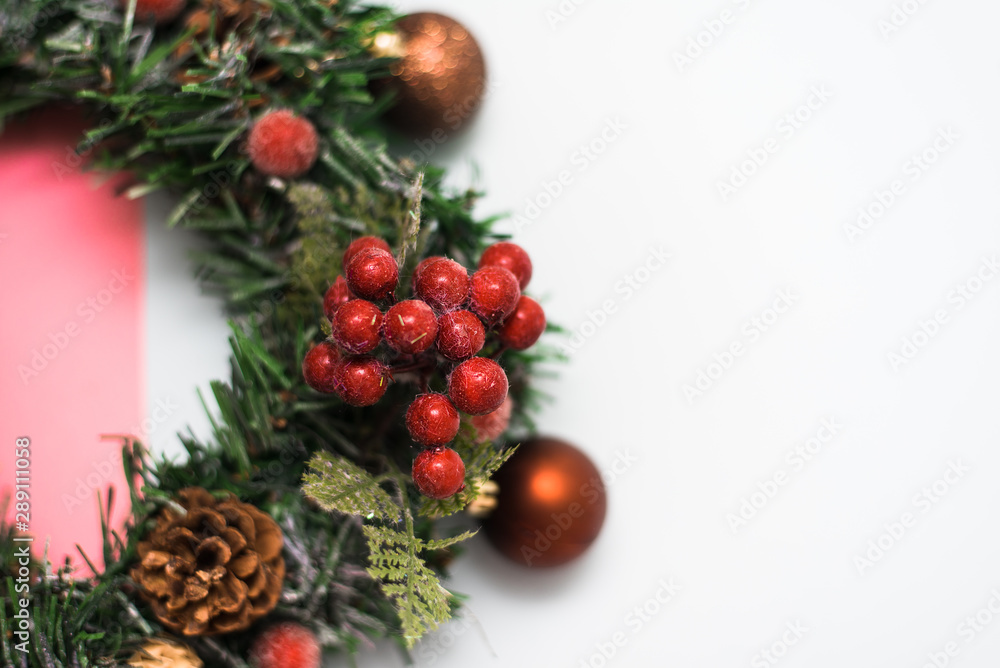 Christmas wreath made of artificial Christmas tree branches, Christmas toys and red berries on a pastel pink and beige background. top view Christmas wreath made of artificial Christmas tree branches, Christmas toys and red berries on a pastel pink and beige background. top view