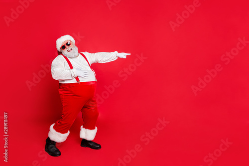 Full body photo of comic bully fat overweight santa claus with funny big belly point at loser laugh wear overalls suspenders have stylish trendy style eyewear isolated over red background © deagreez