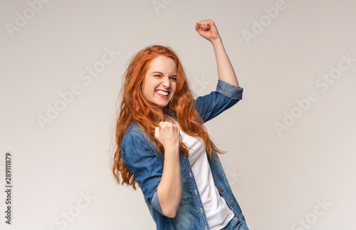 Millennial Girl Shaking Fists Celebrating Success On Light Studio Background