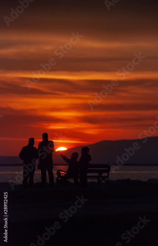 People near seaside in sunset silhouetteof people.