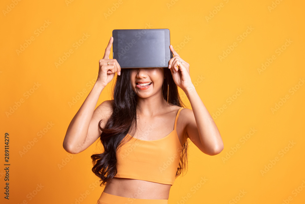 Young Asian woman with a computer tablet over her face. Young Asian woman with a computer tablet over her face.
