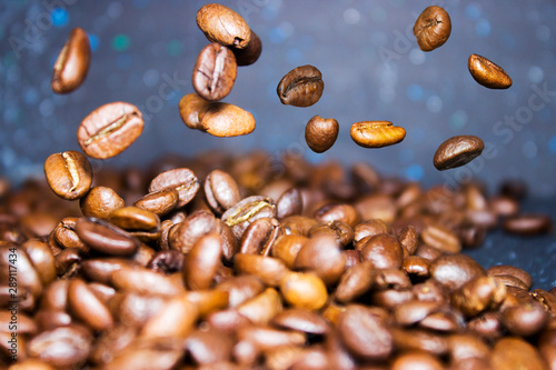 Roasted coffee beans pour from above  hovering in the air on a dark background. Side view  close-up